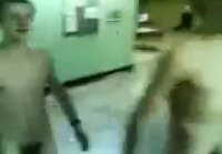 Two naked soldiers stagger down the hall