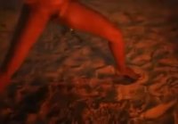 A crowd of women drinking beer and having fun near the fire on a wild beach