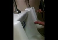 Two slim dicks getting wanked at the urinals